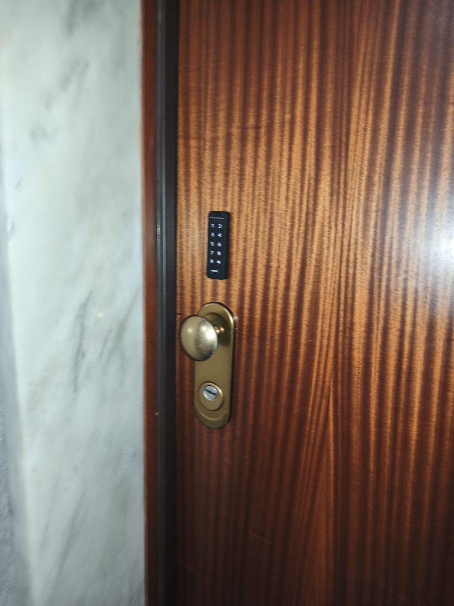 Teclado de códigos ao lado do puxador numa porta de apartamento
